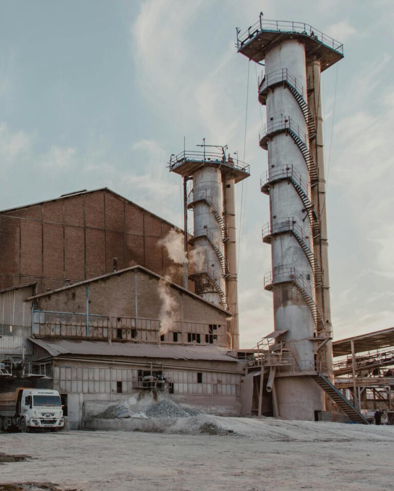 Low angle of pipes and building of industrial factory emitting smoke and polluting air